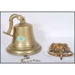 A 20th Century large brass ships style bell with wall hanging bracket attached together with a