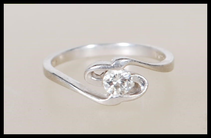 A 950 platinum solitaire diamond ring having an openwork swirl mount set with a single diamond