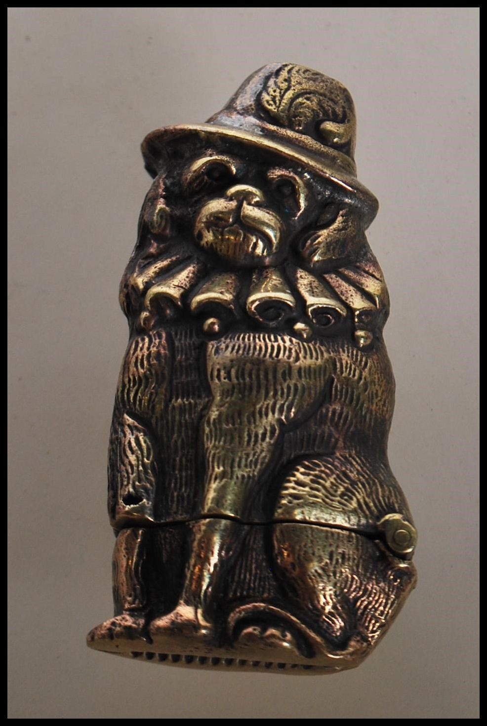 A novelty brass vesta case in the form of a dog wearing a hat and ruff collar. Hinged base with