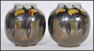 A pair of early 20th Century Royal Doulton ceramic vases of globular form having hand painted