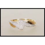 A stamped 375 9ct gold ring having cross over design illusion set with white stones. Weight 1.7g.