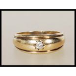 A stamped 375 9ct gold ring gypsy set with a round cut diamond. Weight 4.7g. Diamond estimated at