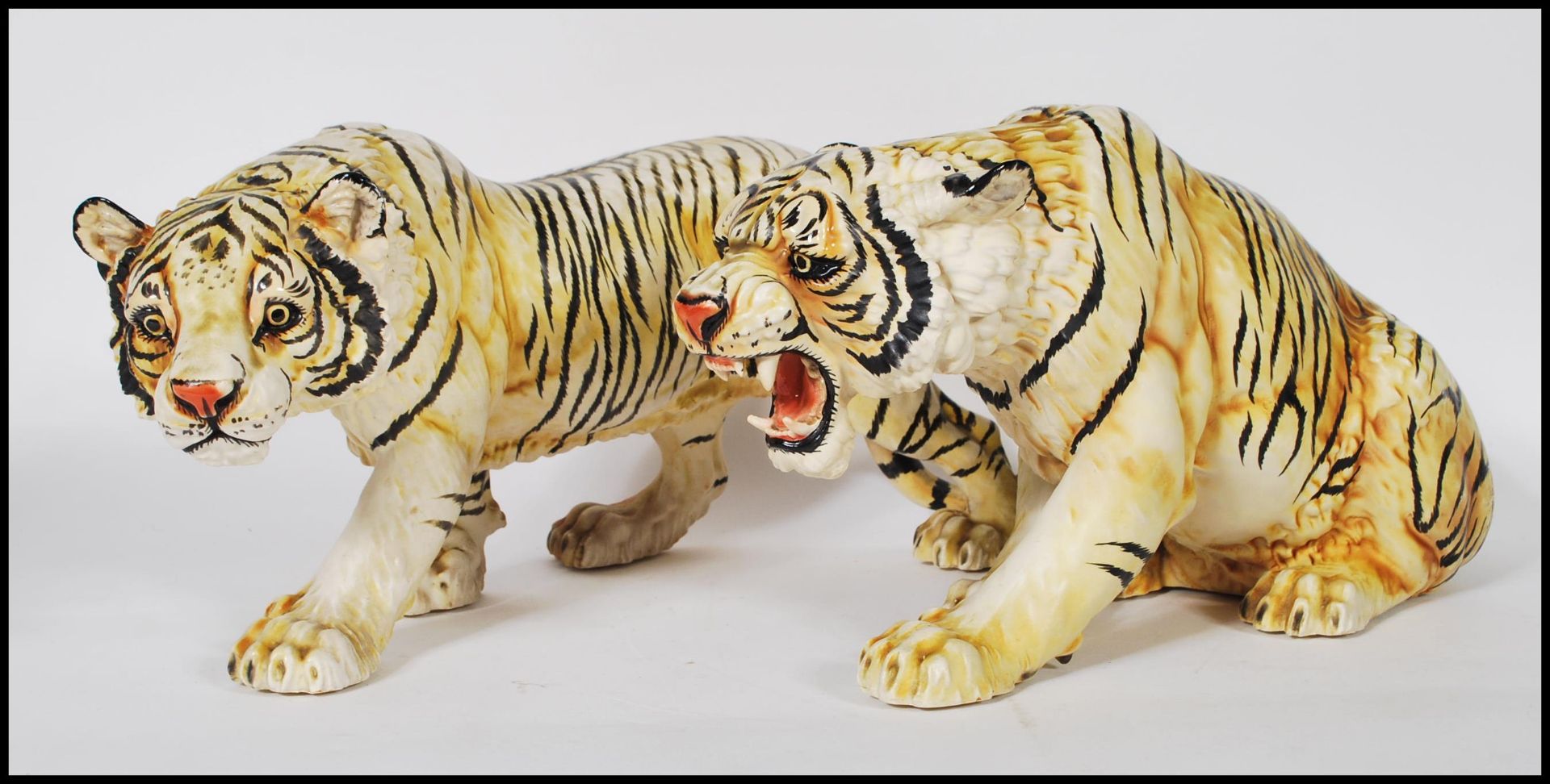 A pair of 20th Century cast resin figurines of tigers having hand painted features to include one