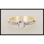 An 18ct yellow gold solitaire diamond ring having platinum shoulders with illusion set diamonds.