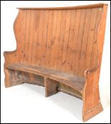A 19th Century Georgian pine tavern wing settle of high back curved form having a plank back with