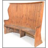 A 19th Century Georgian pine tavern wing settle of high back curved form having a plank back with