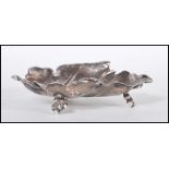 A sterling silver footed dish in the form of a grape leaf with embossed detailing raised on three