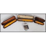 A group of three leather cased butterscotch amber bakelite cheroot holders dating from the early