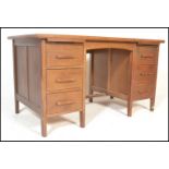 A mid century Air Ministry style oak twin pedestal desk raised on squared legs with a series of