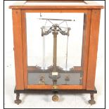 An early 20th Century wooden cased scientific scales in brass set to a black glass base with