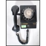 A vintage retro mid 20th Century wall hanging telephone having a black bakelite body with a