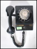 A vintage retro mid 20th Century wall hanging telephone having a black bakelite body with a