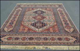 A large 20th Century Persian style woolen floor rug carpet on a neutral ground, polychrome central