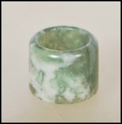 A 20th Century Chinese large mottled dark green and red jade archer's thumb ring of cylindrical