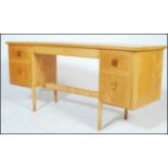 A vintage mis 20th Century beech kneehole writing desk of concave form, having a configuration of