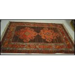 An early 20th Century Persian Islamic carpet floor rug having a central brown panel with two large