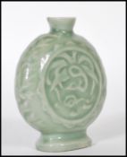 A 19th Century Chinese ceramic bottle / moon flask having a green glaze finish with floral relief