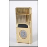 A gold tone rectangular Ronson cigarette lighter having a striped textured body with fold out