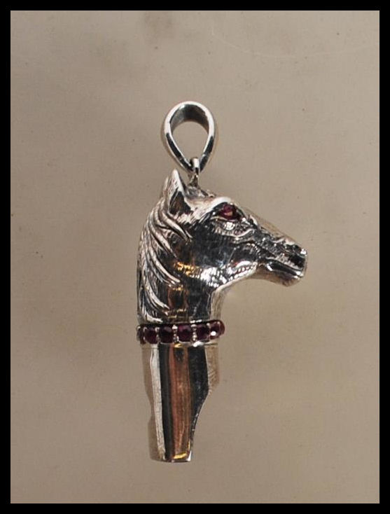 A silver novelty whistle pendant in the form of a horse head set with ruby eyes and having a ruby