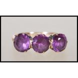 A stamped 9ct yellow gold ladies dress ring prong set with three purple stones on a decorative
