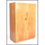 An original Gordon Russell walnut double wardrobe. Raised on plinth base with full length doors