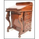 A 20th Century Victorian-style walnut davenport with sloping fall over four drawers on carved