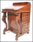 A 20th Century Victorian-style walnut davenport with sloping fall over four drawers on carved