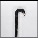 A vintage 20th Century ebony walking stick cane. The handle in the form of an elephant with carved