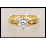 A stamped 18ct yellow gold ring having a decorative raised mount set with a single solitaire diamond