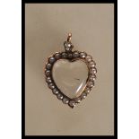 A hallmarked 9ct gold Edwardian locket pendant in the form of a heart having a glazed panel to the