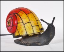 A contemporary bronze effect Tiffany style table lamp in the form of a snail. The glass shell having