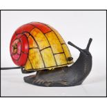 A contemporary bronze effect Tiffany style table lamp in the form of a snail. The glass shell having