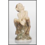 A Royal Copenhagen figurine in the form of a faun / satyr seated on a log. Number 1738. Marks to the