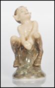 A Royal Copenhagen figurine in the form of a faun / satyr seated on a log. Number 1738. Marks to the