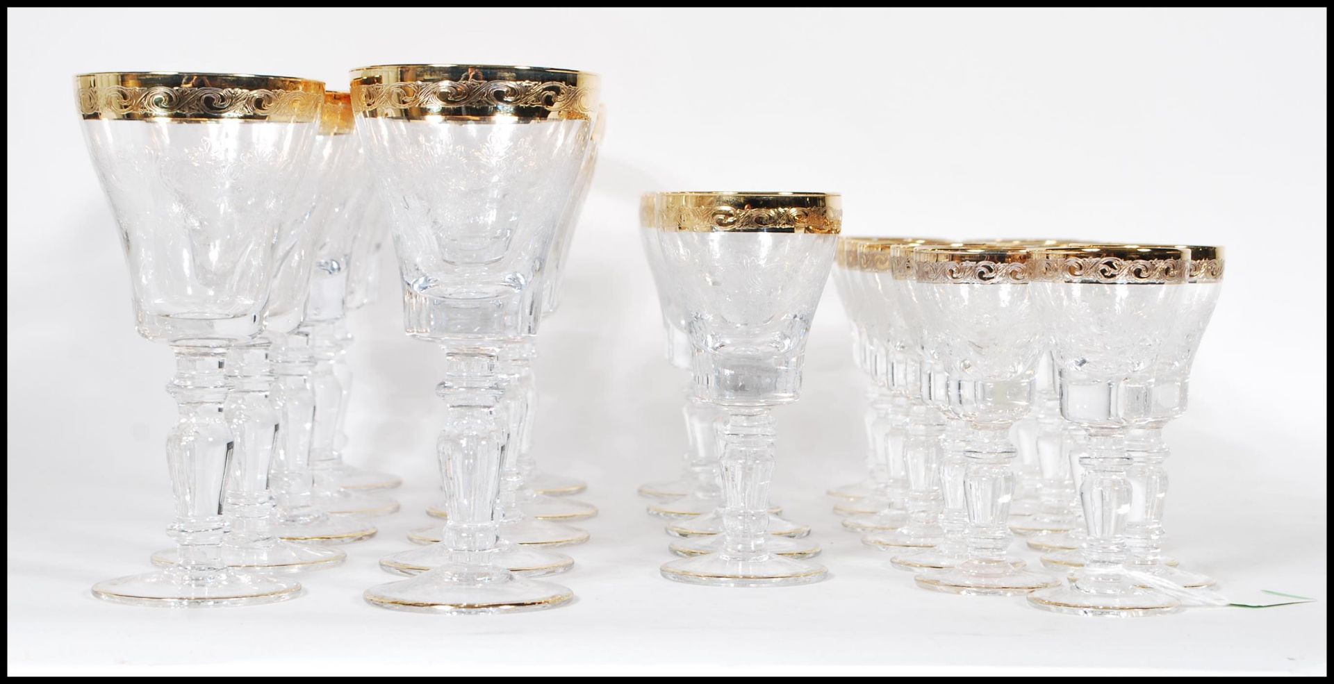 A large collection of glassware having scrolled decoration to the bowls raised on knopped columns on