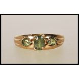 A hallmarked 9ct gold ring with central oval cut green stone flanked by two teardrop green stones on