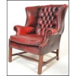 A 20th Century Antique style red leather oxblood Chesterfield wingback armchair raised on straight