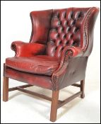 A 20th Century Antique style red leather oxblood Chesterfield wingback armchair raised on straight