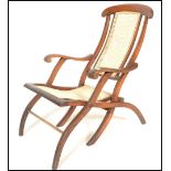 An early 20th Century campaign folding steamer chair of beech construction having caned backrest and