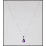 A stamped 18ct white gold pendant necklace having a central faceted cut amethyst with a halo of
