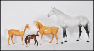 A group of four Beswick horses to include a large gray and white stallion with black hooves, two