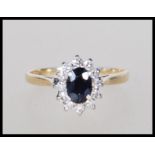 A hallmarked 9ct gold ring set with an oval cut sapphire with a halo of white stones. Hallmarked