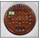 A 20th Century solitaire board game having a full set of coloured swirl glass marbles on a