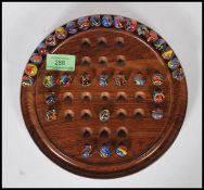 A 20th Century solitaire board game having a full set of coloured swirl glass marbles on a