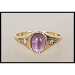 A 9ct gold English hallmarked ring set with a central purple cabochon stone flanked by two white