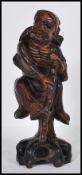 An early 20th Century Chinese carved hardwood figure of an Immortal holding a gnarled staff with one