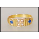 A hallmarked 15ct gold ring set with four seed pearls flanked by two gypsy set sapphires. Hallmarked
