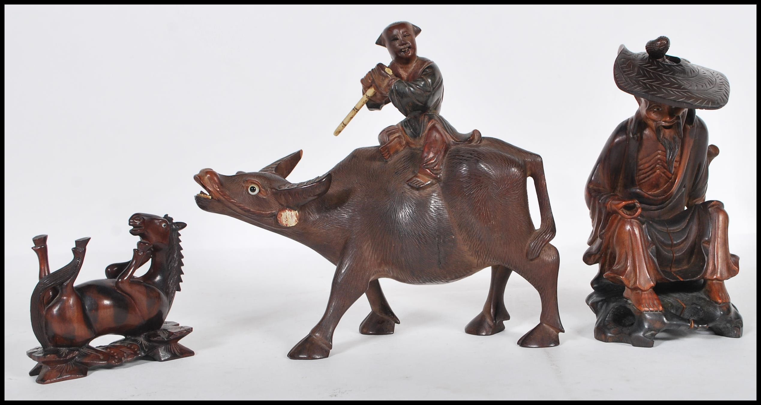 A group of 20th Century Chinese carved hardwood figurines to include a flute player riding on a