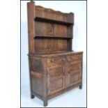 An early 20th Century Jacobean revival elm Welsh dresser of small proportions. Panel cupboards