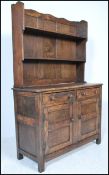 An early 20th Century Jacobean revival elm Welsh dresser of small proportions. Panel cupboards